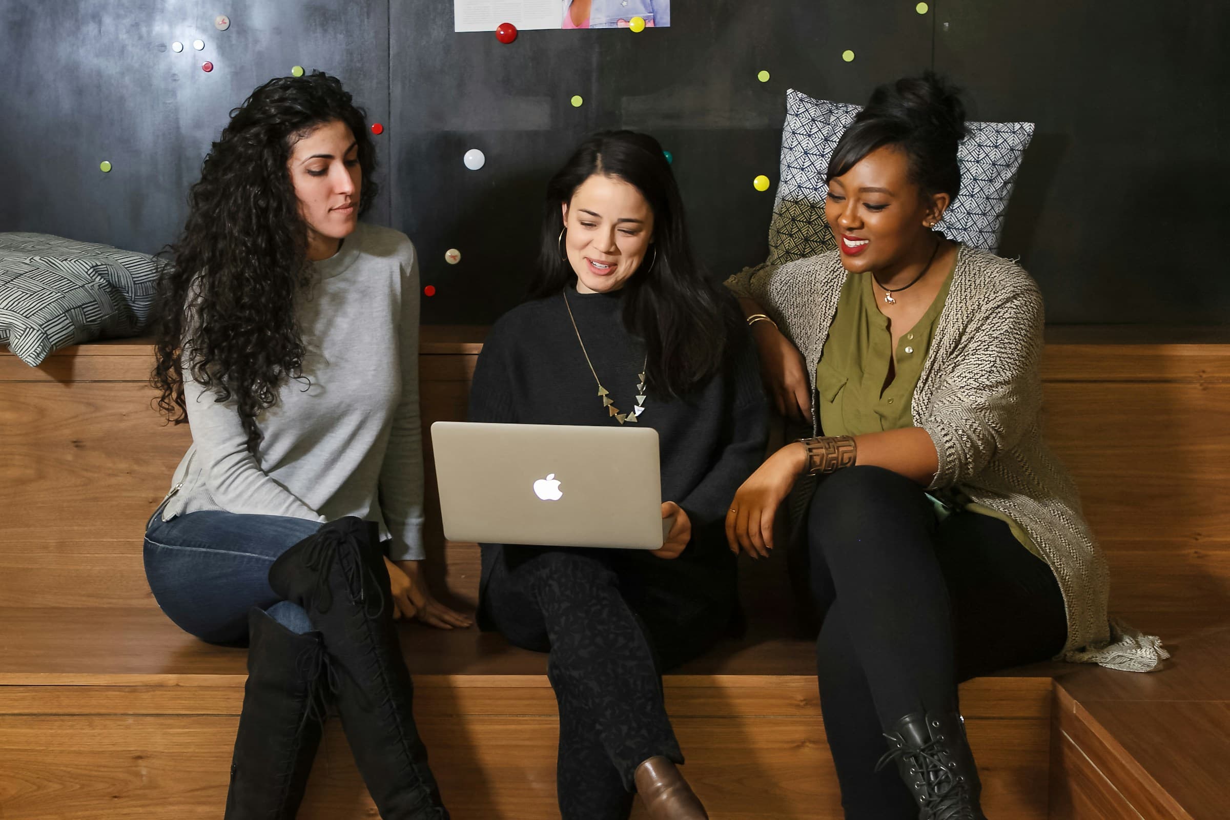 Three women sitting in a shared workspace, working in a laptop together