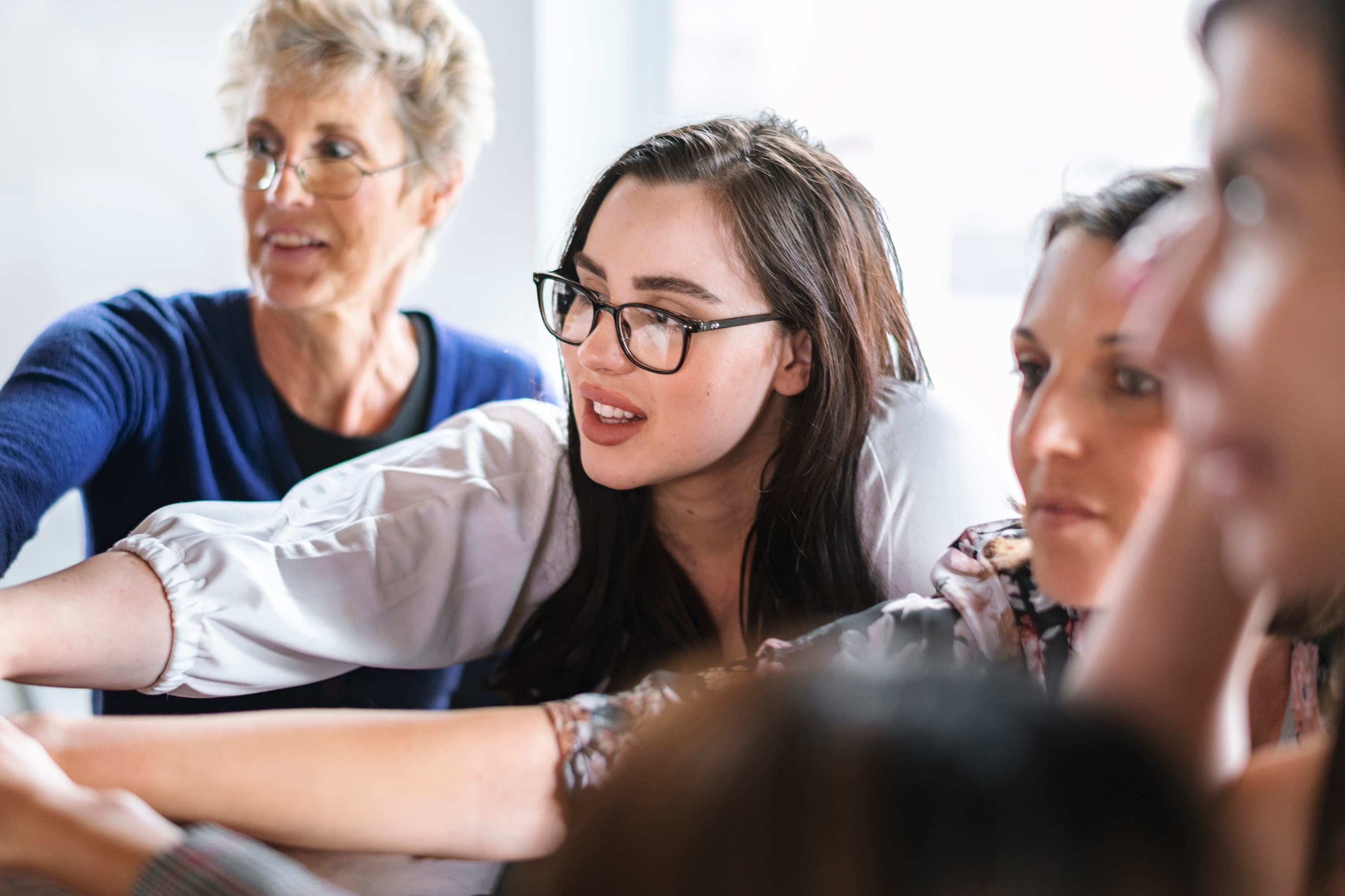 Group of women from differente age groups collaborating and enthusiastically pointing at something off-camera